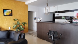 A modern living room with a leather sofa, a potted plant, and a wooden reception desk. - Hotel Vermon (Armenia)