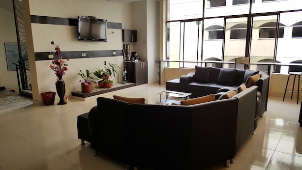 A spacious lobby with a modern sofa set, a flat-screen TV mounted on the wall, and a large window offering a view of the building's exterior. - Hotel Vermon (Armenia)