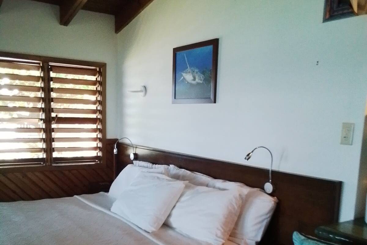 Un dormitorio con cama, mesita de noche, escritorio y silla.