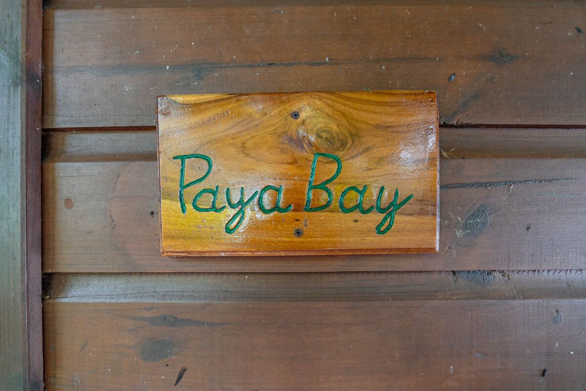 A wooden sign with the text "Paya Bay" on a wooden wall.