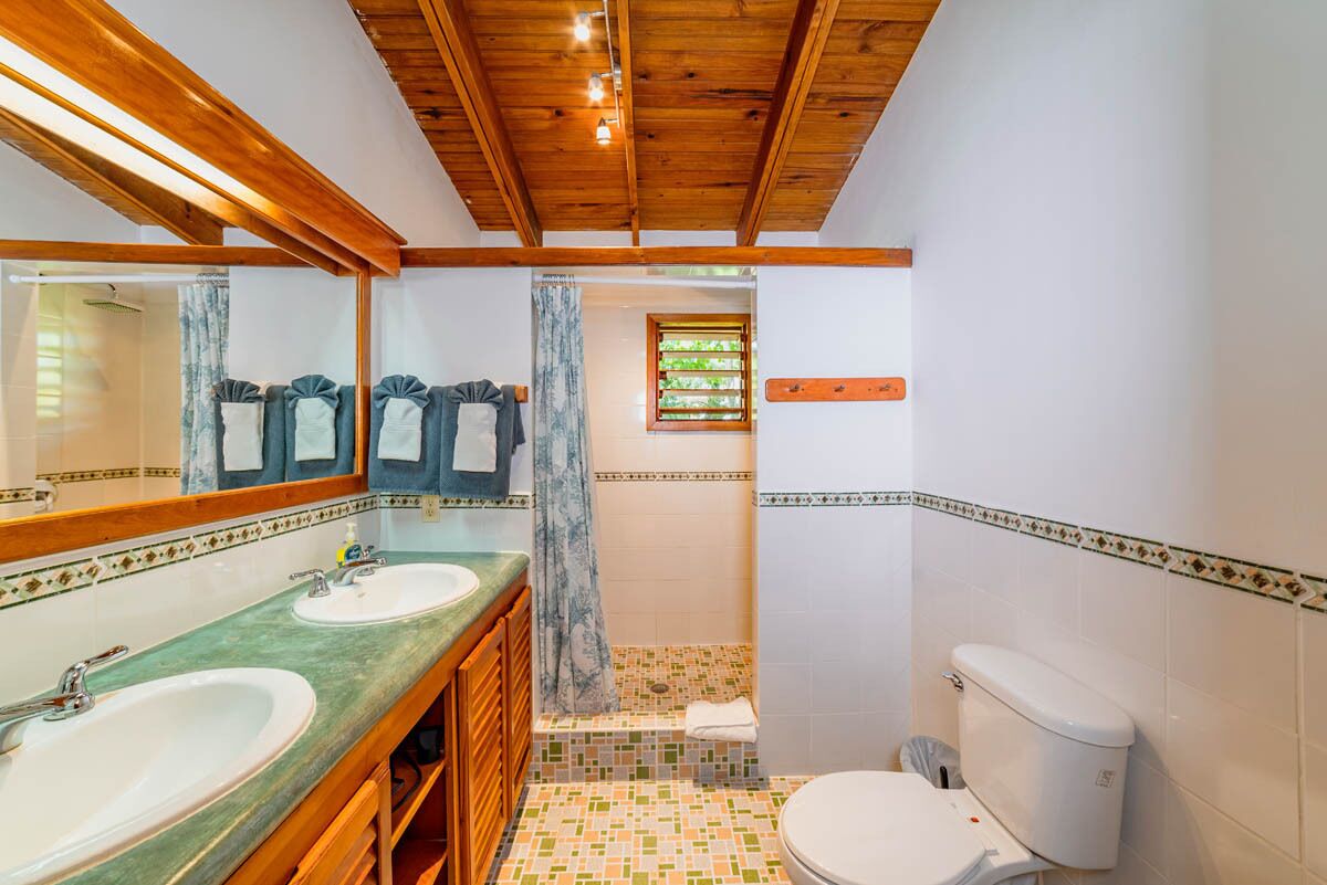 Casa de banho com duas pias, sanita e chuveiro.