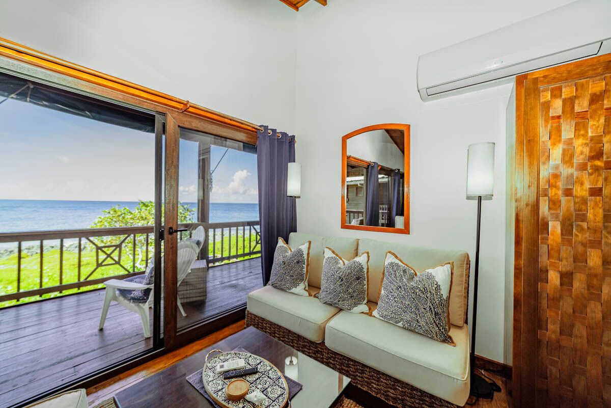A room with a sofa, a coffee table, and a view of the ocean.