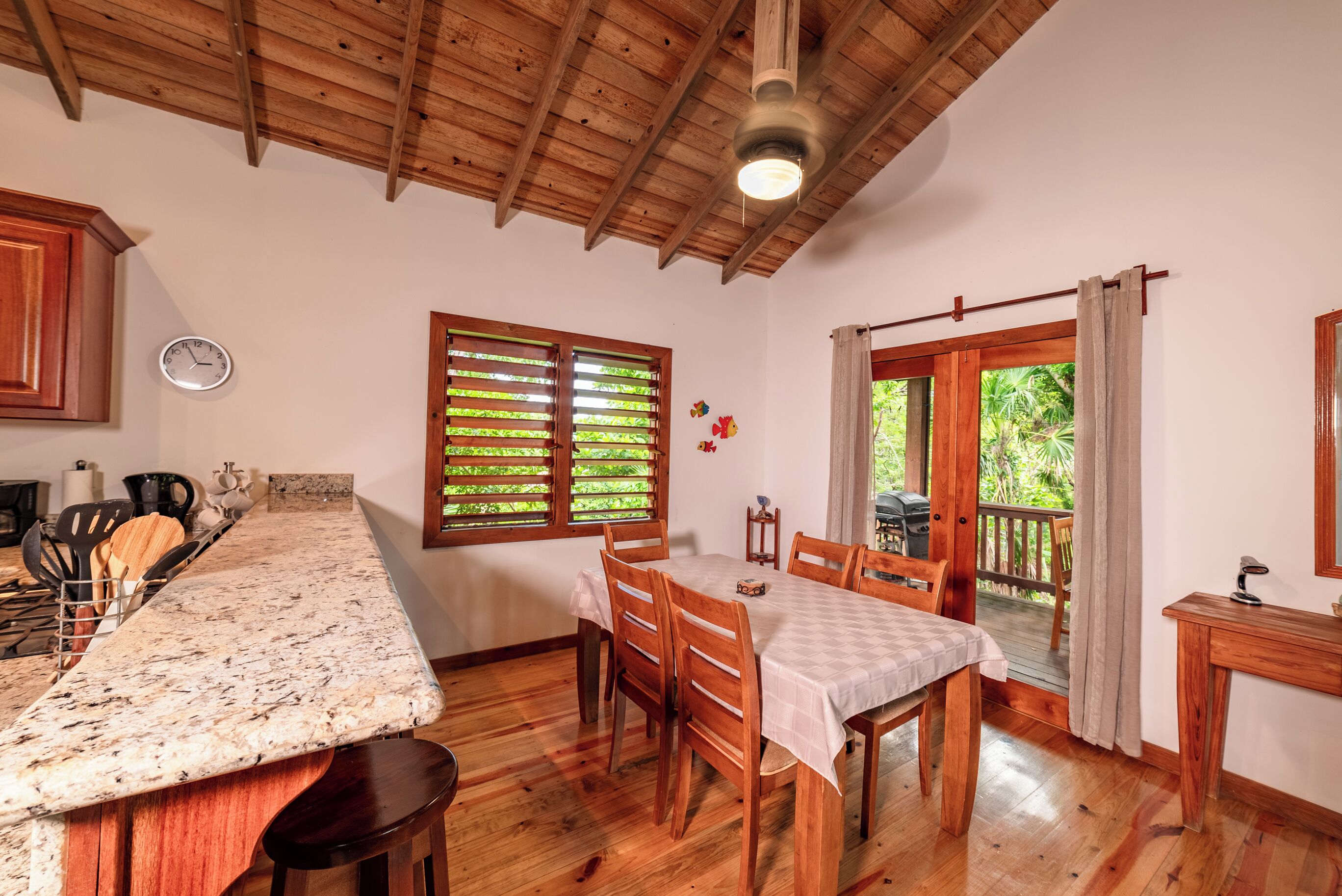 A kitchen with wooden cabinets, a granite countertop, and a dining area with a table and chairs.
