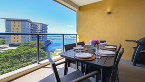 Un balcon avec une table à manger pour quatre personnes, offrant une vue sur une marina et des bâtiments.