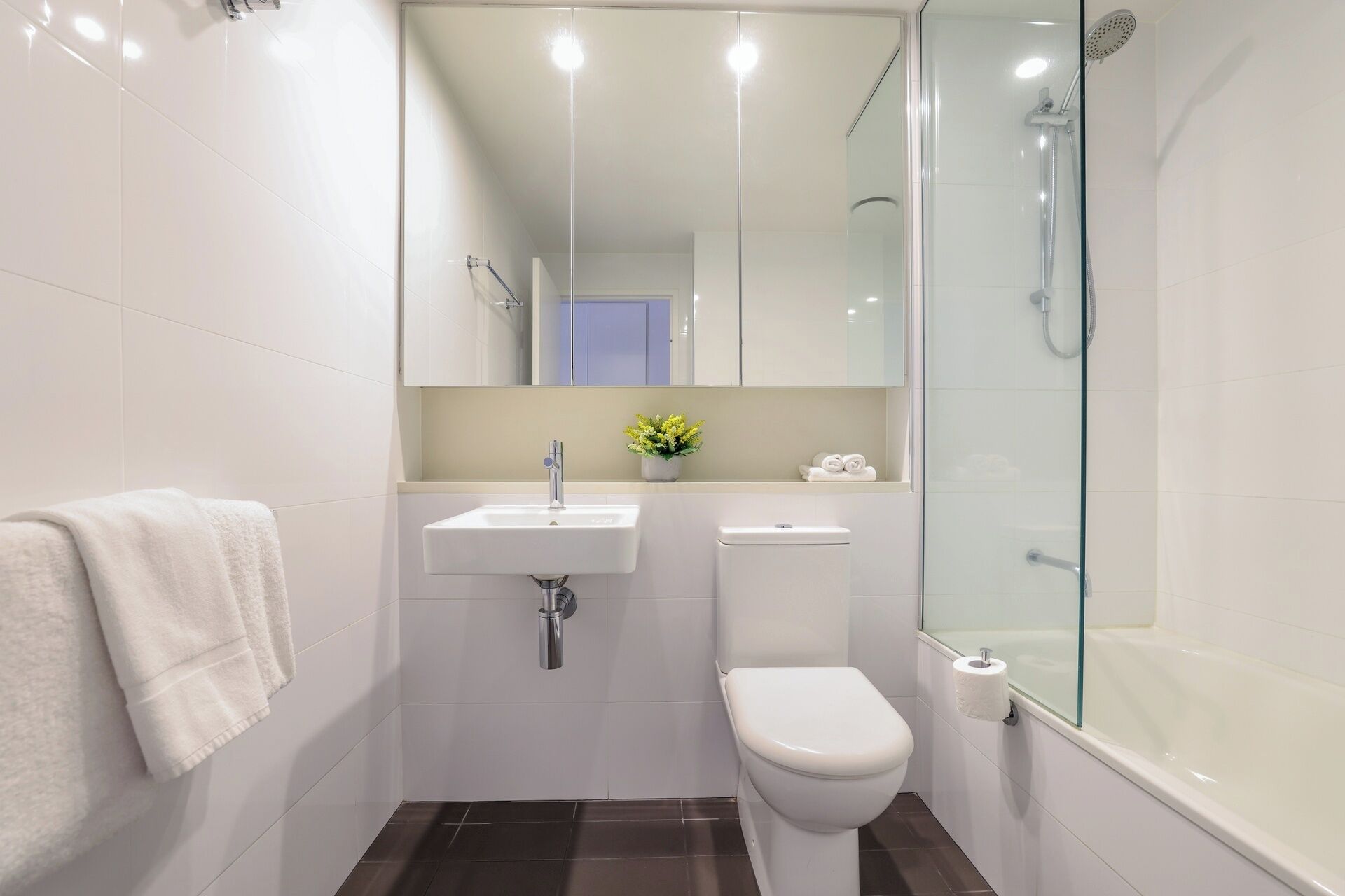 Un baño moderno con cabina de ducha de vidrio, un lavabo blanco y un inodoro.