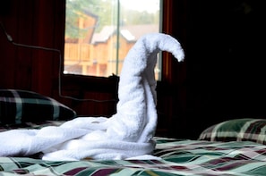 A bed with a white towel shaped like a swan.