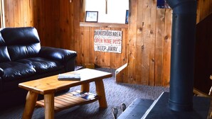 Una estada acollidora amb un sofà de pell negra, una taula baixa de fusta i una llar de foc negra. Un cartell a la paret diu: "DANGEROUS AREAS OPEN MINE PITS KEEP AWAY".