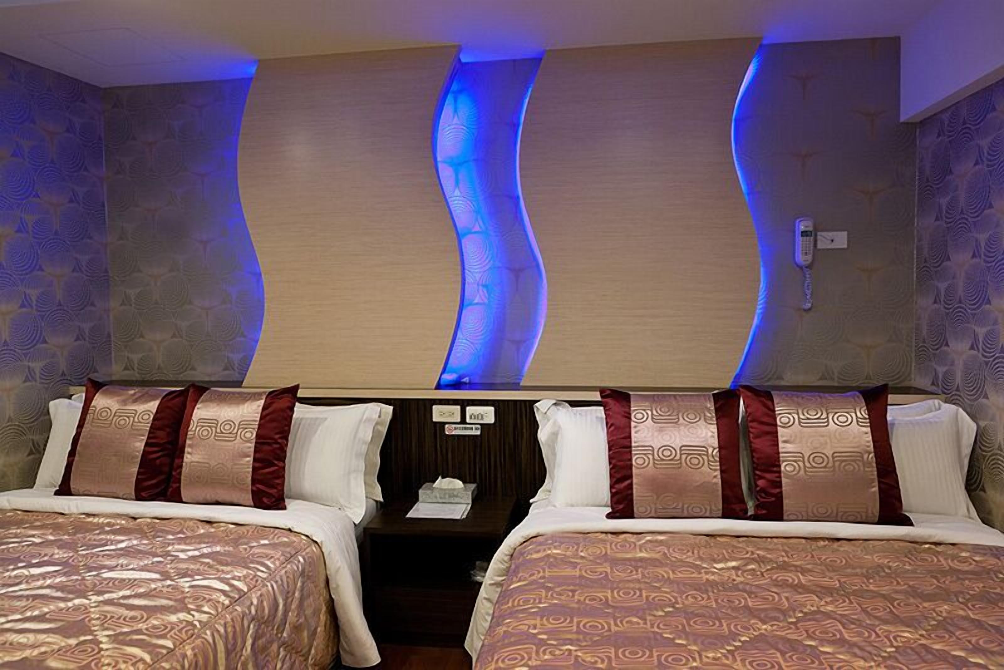 A hotel room with two beds, a wooden headboard, and a wall with a wavy design.