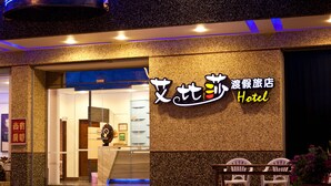 A hotel entrance with a sign in Chinese and English, a staircase leading inside, and a seating area with chairs outside. - Ibiza Kenting Hotel (Hengchun)