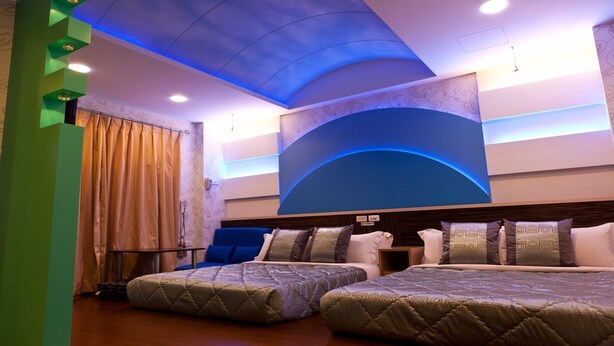 A hotel room with two beds, a large arched wall design, and a ceiling with blue lighting. - Ibiza Kenting Hotel (Hengchun)