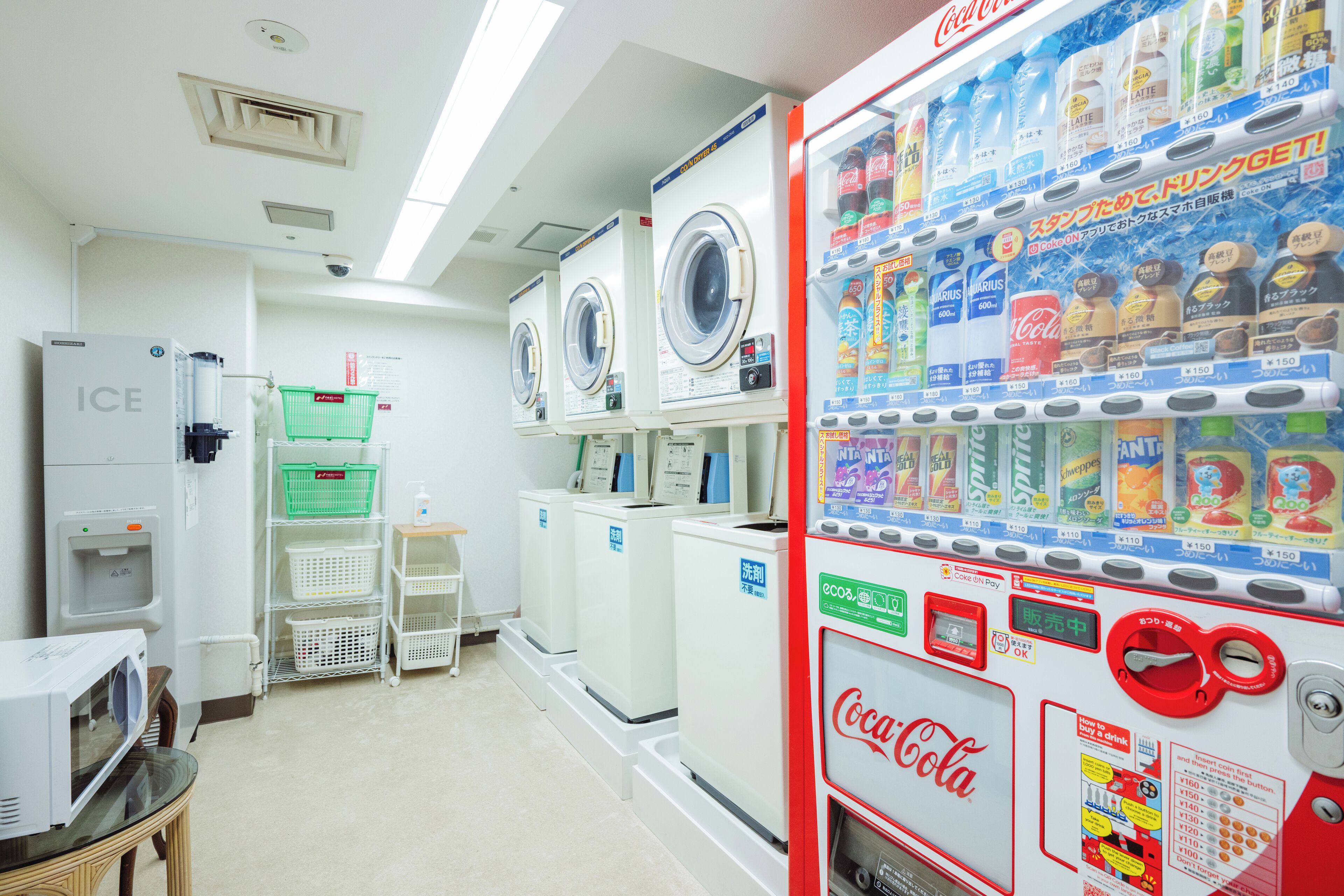 Eine Waschsalon mit mehreren Waschmaschinen und Trocknern, einem Coca-Cola Automaten und einem Wasserspender.