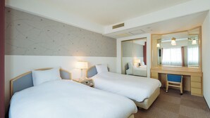 Habitación de hotel con dos camas, un escritorio, una silla, un espejo y una lámpara.