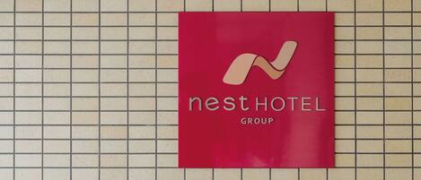 Letrero del grupo hotelero Nest en una pared de azulejos.
