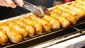 En person griller pølser på en grill.