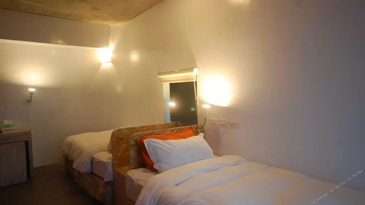A room with two beds, a wooden headboard, and a nightstand.