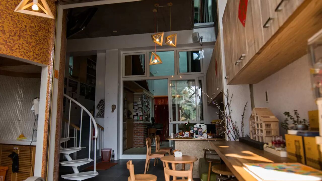 Un interior moderno con escalera, muebles de madera e iluminación colgante.