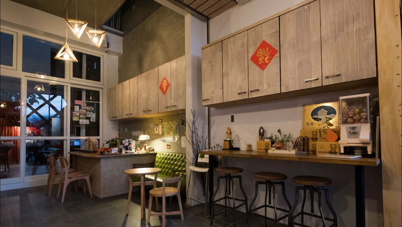 A modern kitchen with wooden cabinets, a green cushioned seating area, and bar stools.
