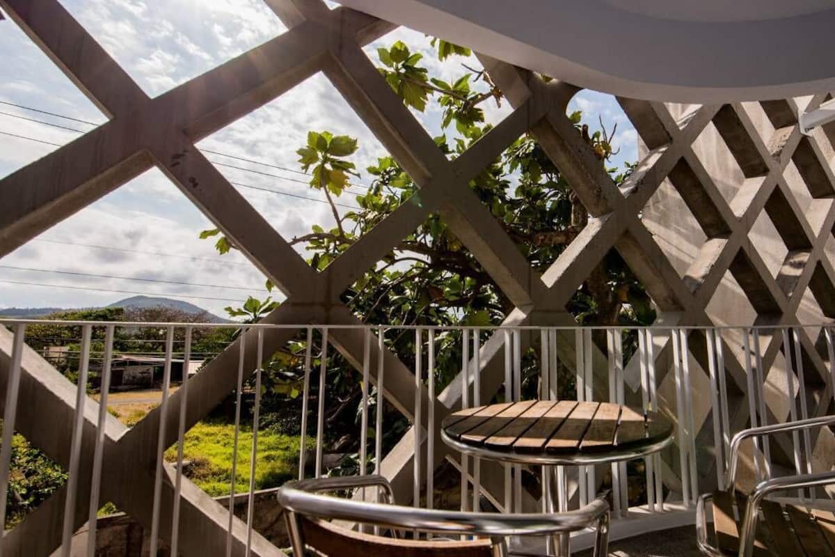 A balcony with a lattice structure, two metal chairs, and a small round table.