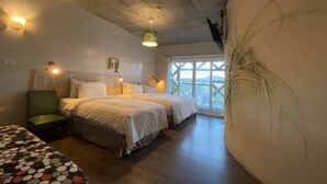 Un dormitorio con dos camas, una silla verde, una mesa con motivos y un ventanal con vistas.
