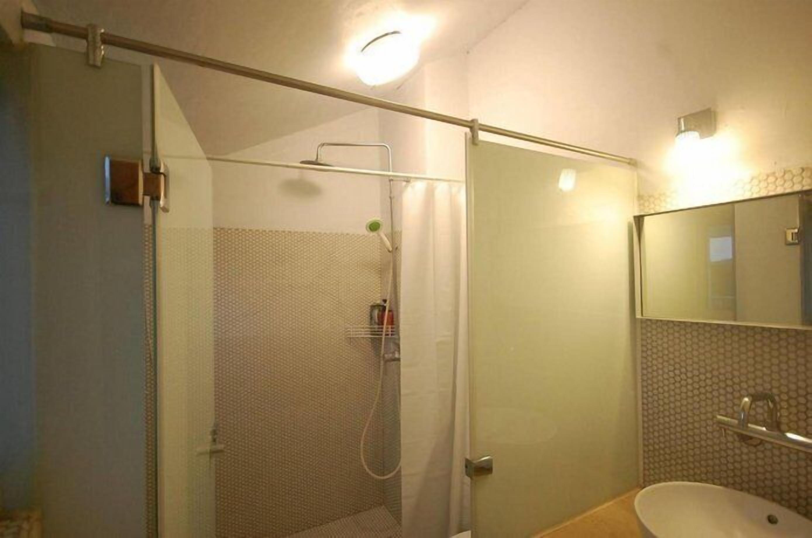A bathroom with a glass-enclosed shower, a sink, and a mirror.