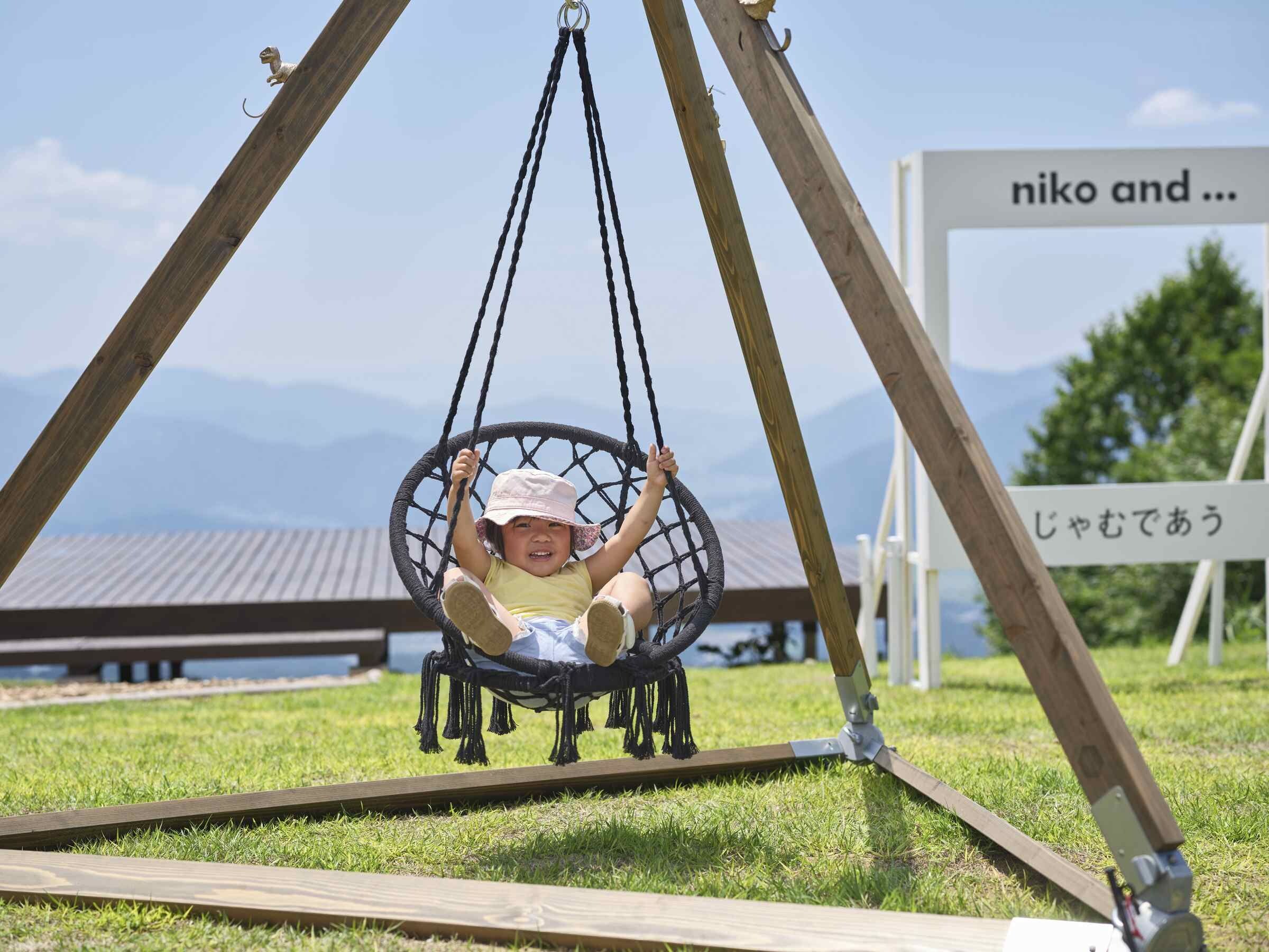 Un enfant sur une balançoire, avec une vue sur les montagnes en arrière-plan.