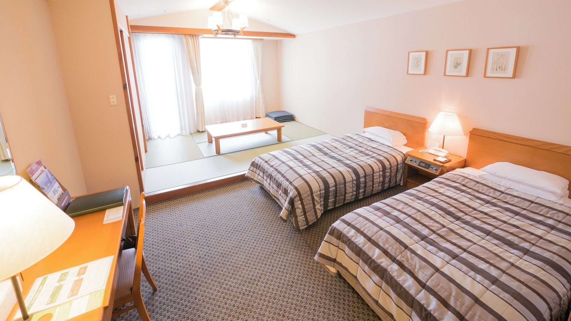Een hotelkamer met twee bedden, een bureau met lamp, een stoel, een kleine tafel en een spiegel.