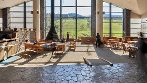 A spacious interior with large windows, stone flooring, and wooden furniture.