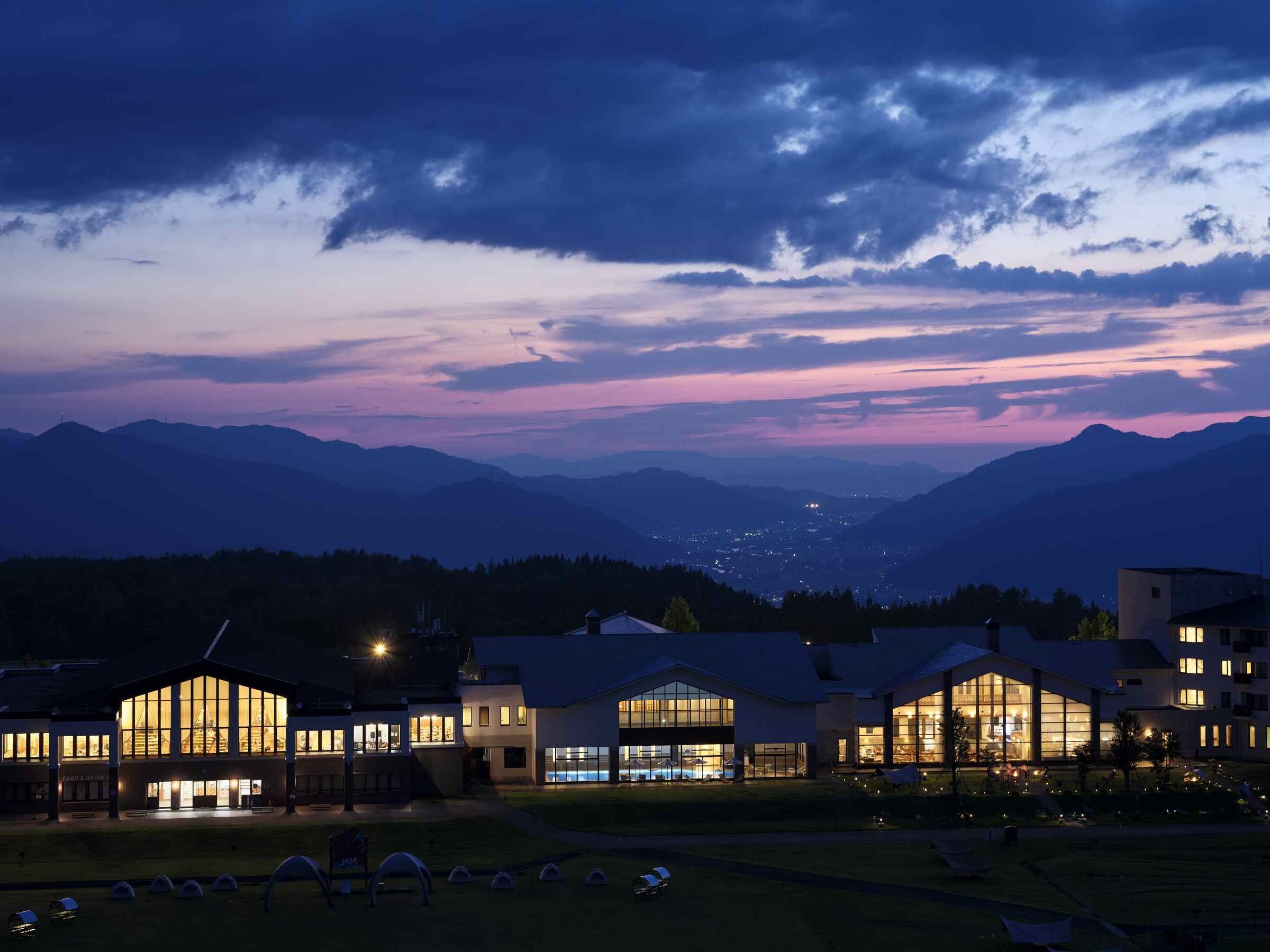 A hotel with multiple buildings, large windows, and a view of mountains in the background.
