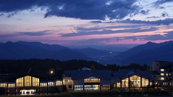 A hotel with multiple buildings, large windows, and a view of mountains in the background.