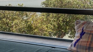Vista desde una ventana que muestra un lago, colinas y árboles.