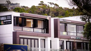 Un edificio moderno con letreros que indican Hakalodge Backpackers y el café-restaurante Upper Deck.