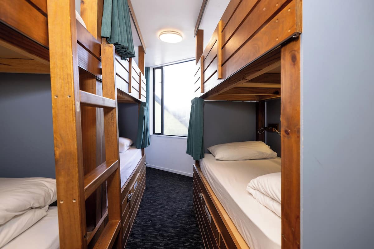 Un cuarto pequeño con literas de madera y una ventana.