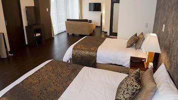 Una habitación de hotel con dos camas, un sofá, un televisor y un escritorio.