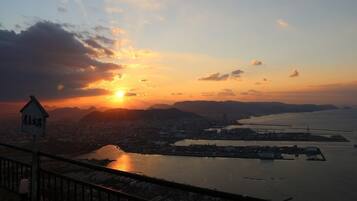 A sunset view from a high vantage point overlooking a cityscape and a body of water.
