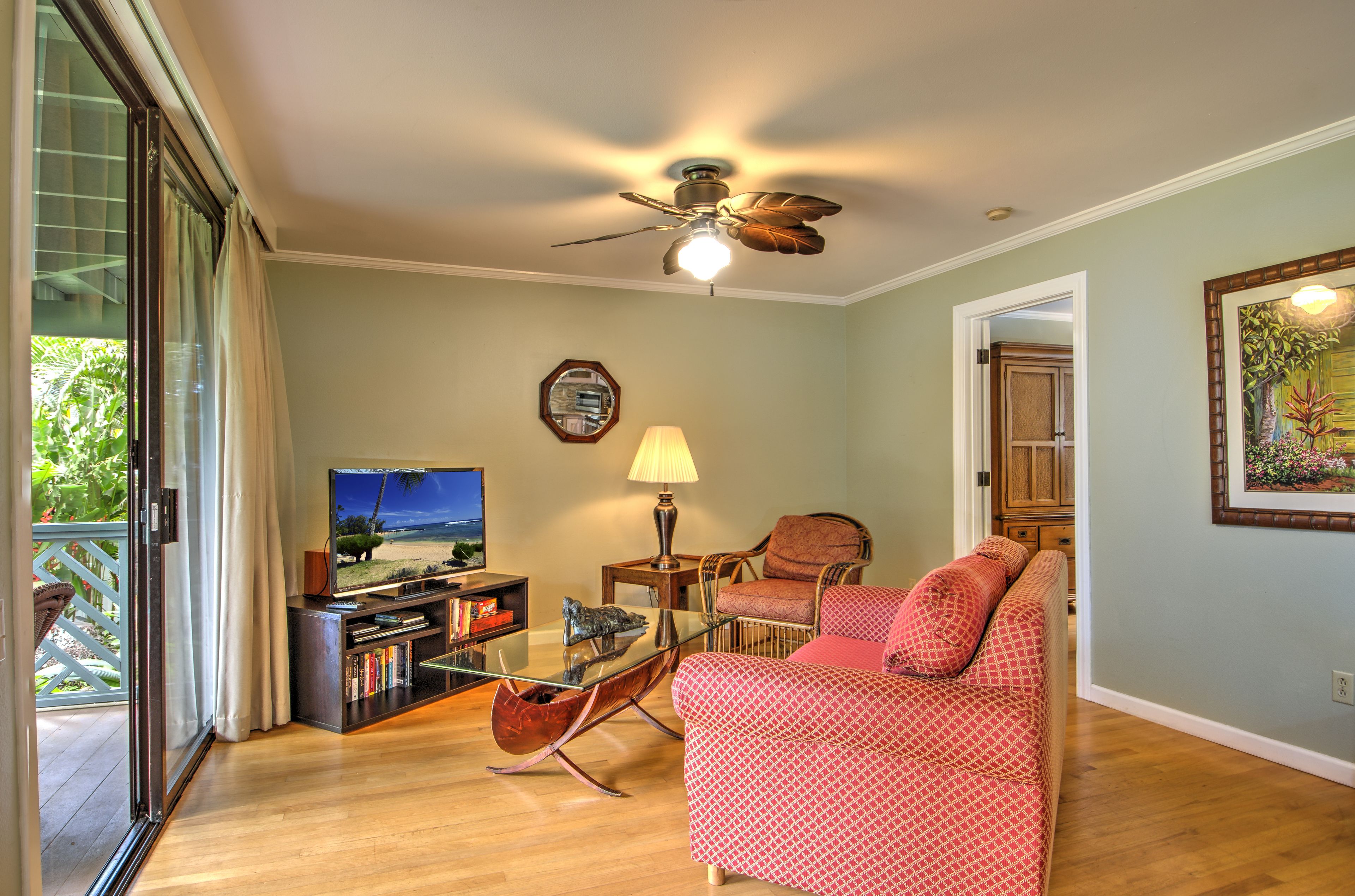 Un salon équipé d’un ventilateur de plafond, d’un téléviseur, d’un canapé, d’une table basse et d’une bibliothèque.