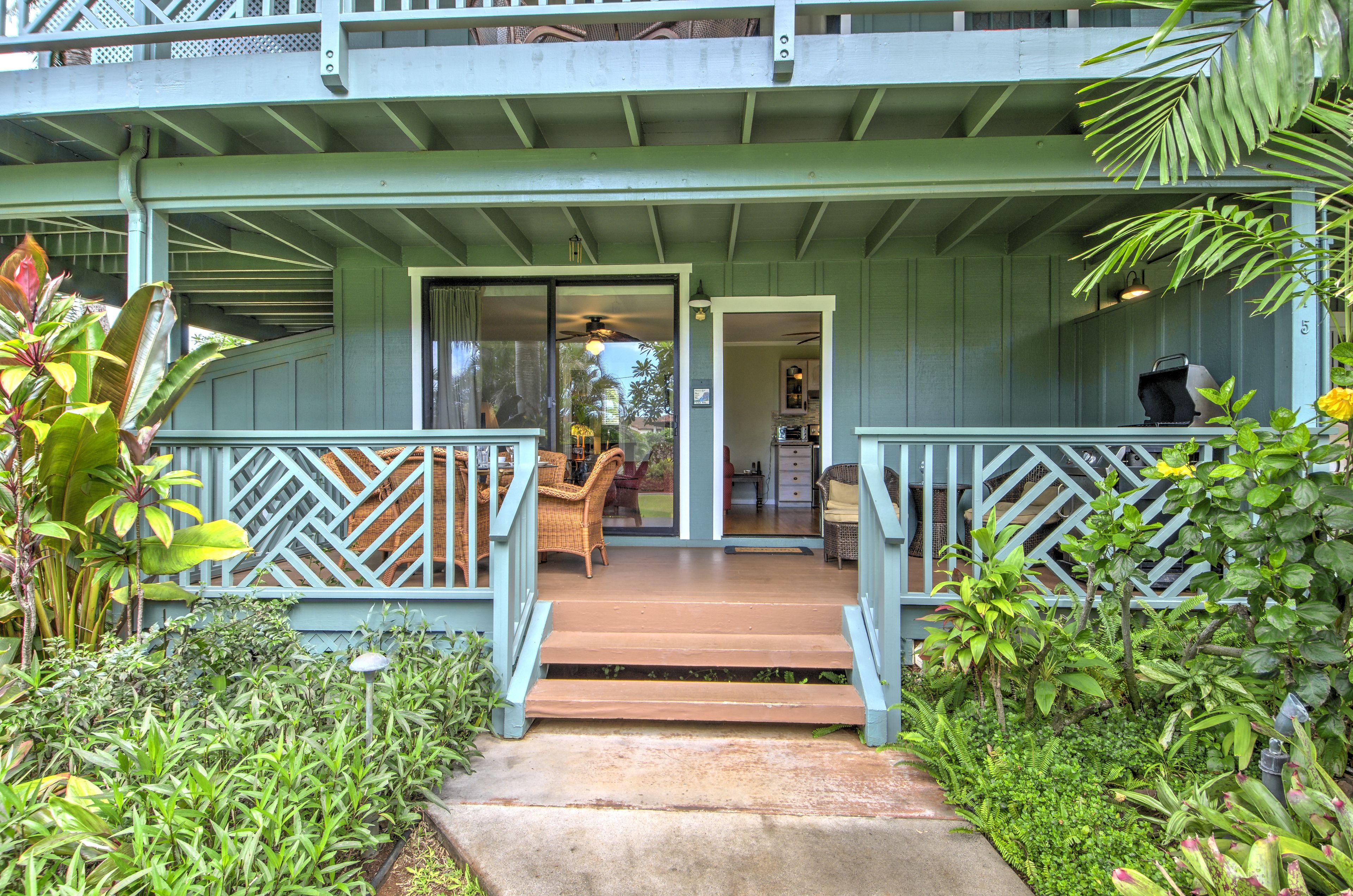 A porch with a wooden deck, wicker furniture, and a view into the house.