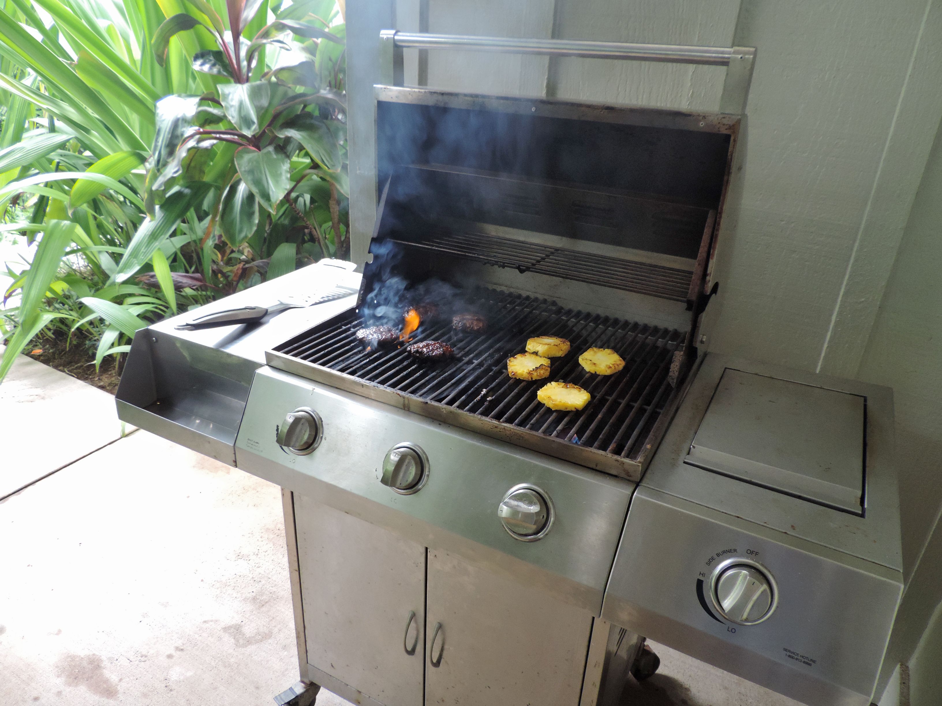 Un barbecue en acier inoxydable doté de quatre grilles, d’un brûleur latéral et d’un panneau de commande avec des boutons.