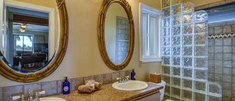A bathroom with two sinks, a toilet, and a shower with glass block walls.
