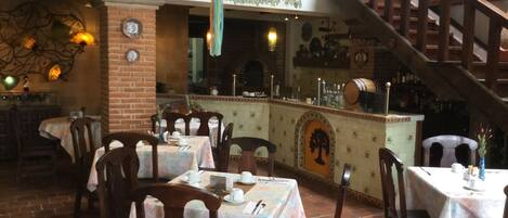 Un restaurante con paredes de ladrillo, mesas de madera y lámparas colgantes.