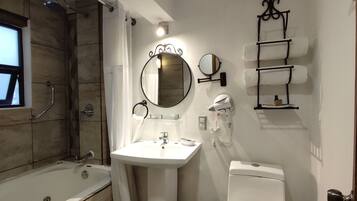 A bathroom with a bathtub, a sink, a toilet, a mirror, and a towel rack.