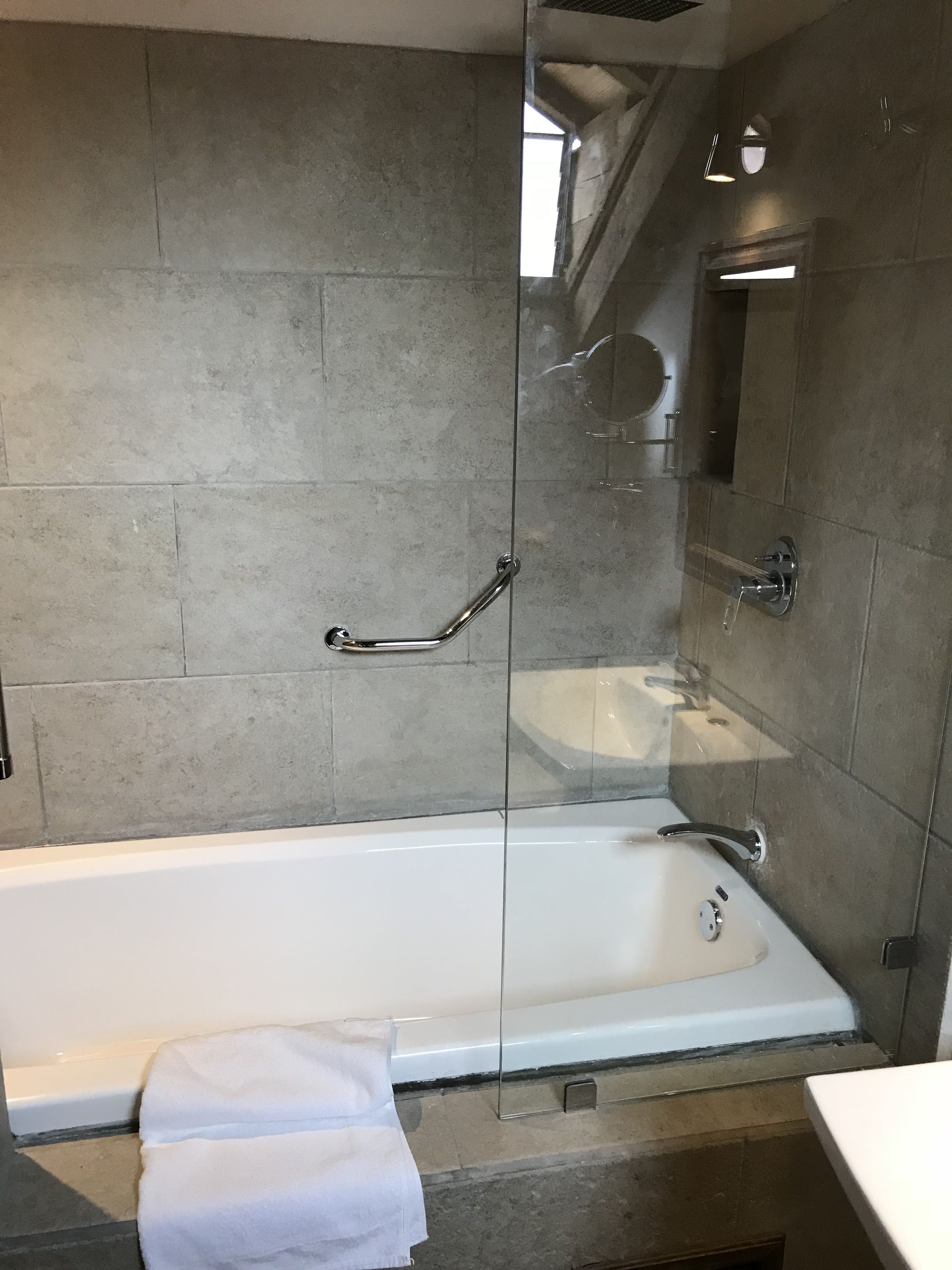 Ein modernes Badezimmer mit einer gläsernen Duschkabine, einer weißen Badewanne und einem separaten Waschbecken.