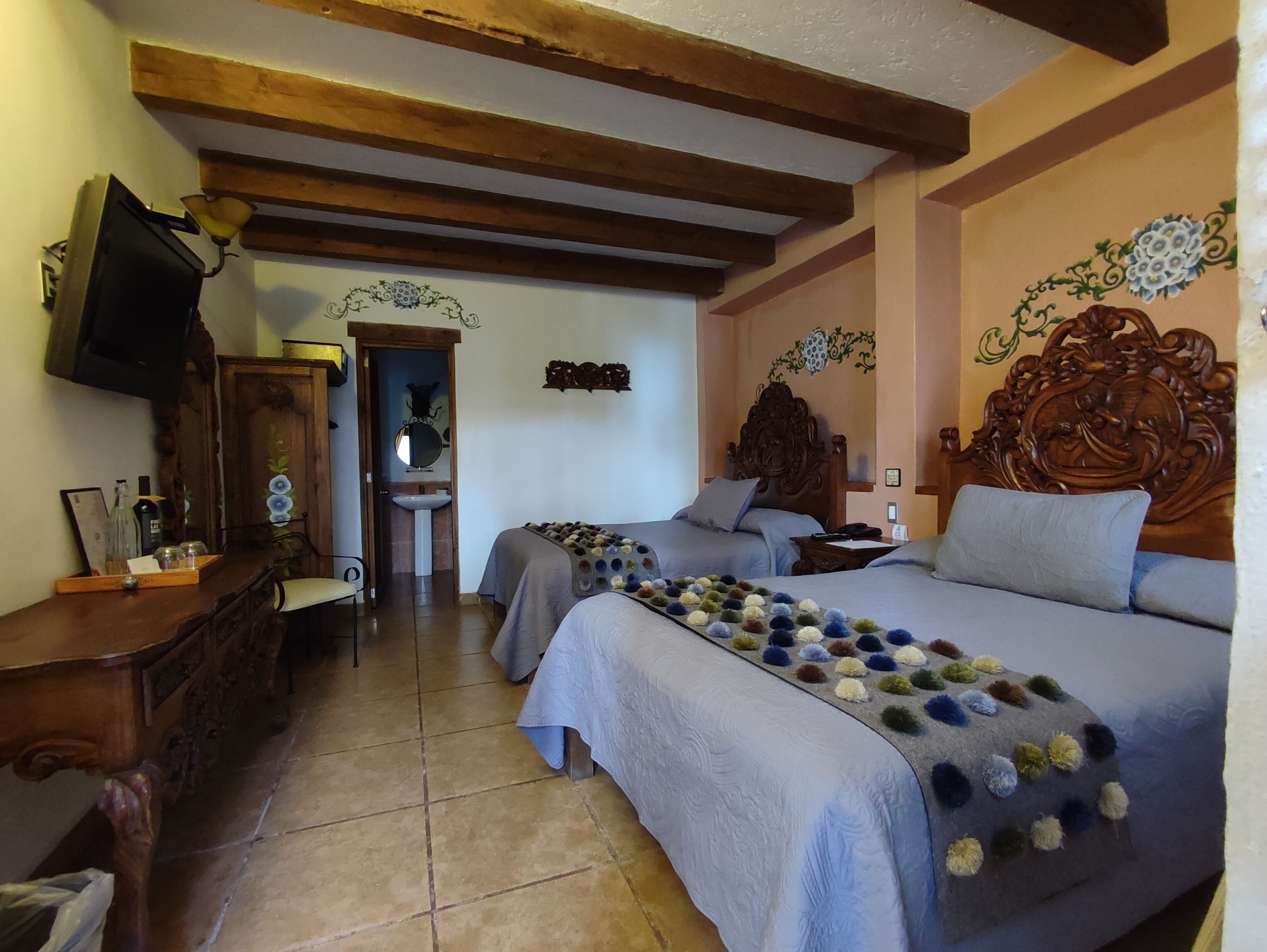 A room with two beds, a wooden dresser, a television, and a mirror.