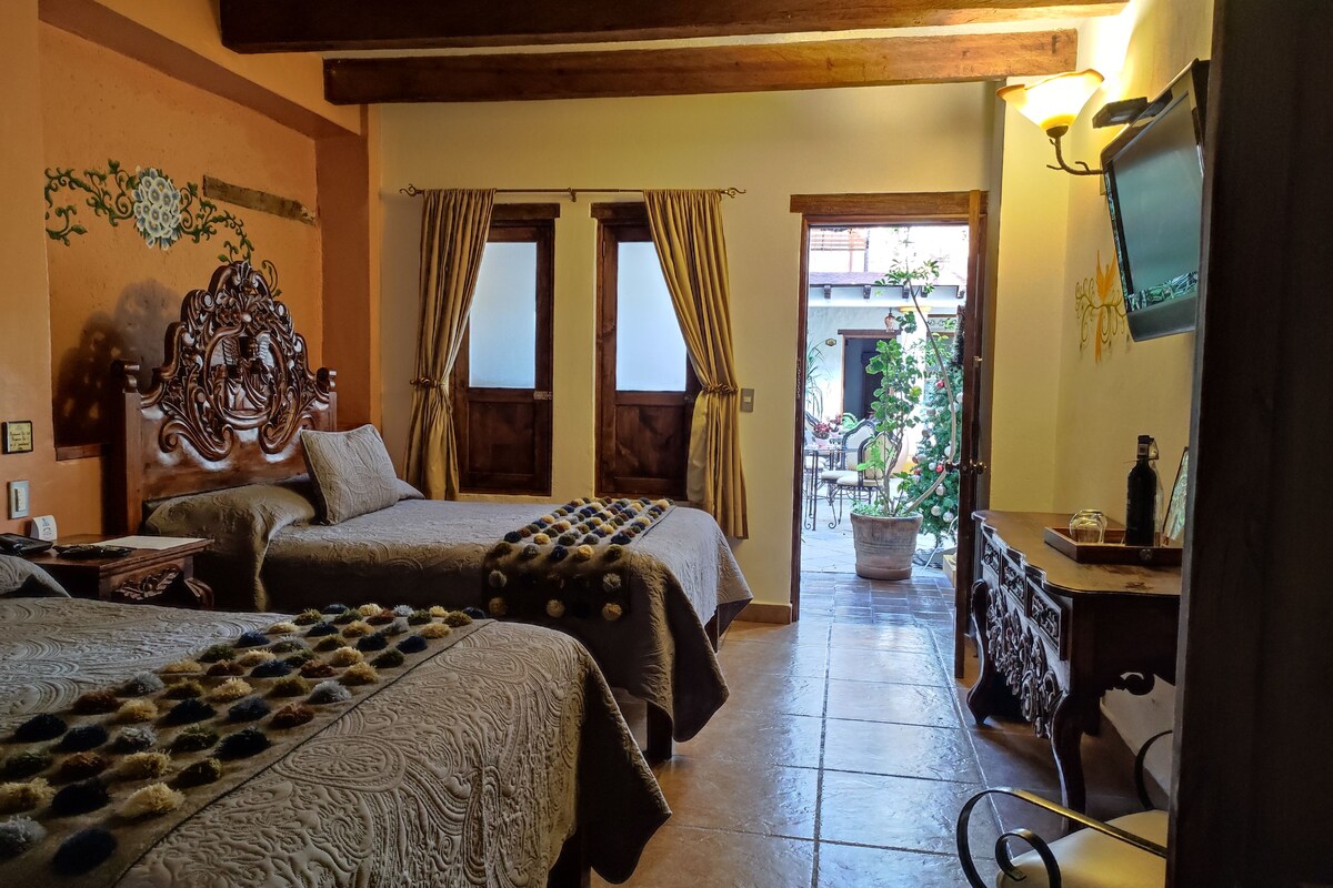 Habitación con dos camas, cabecero de madera, televisor y vista al exterior.