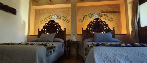 A hotel room with two beds, wooden headboards, a textured wall, and a window with curtains.