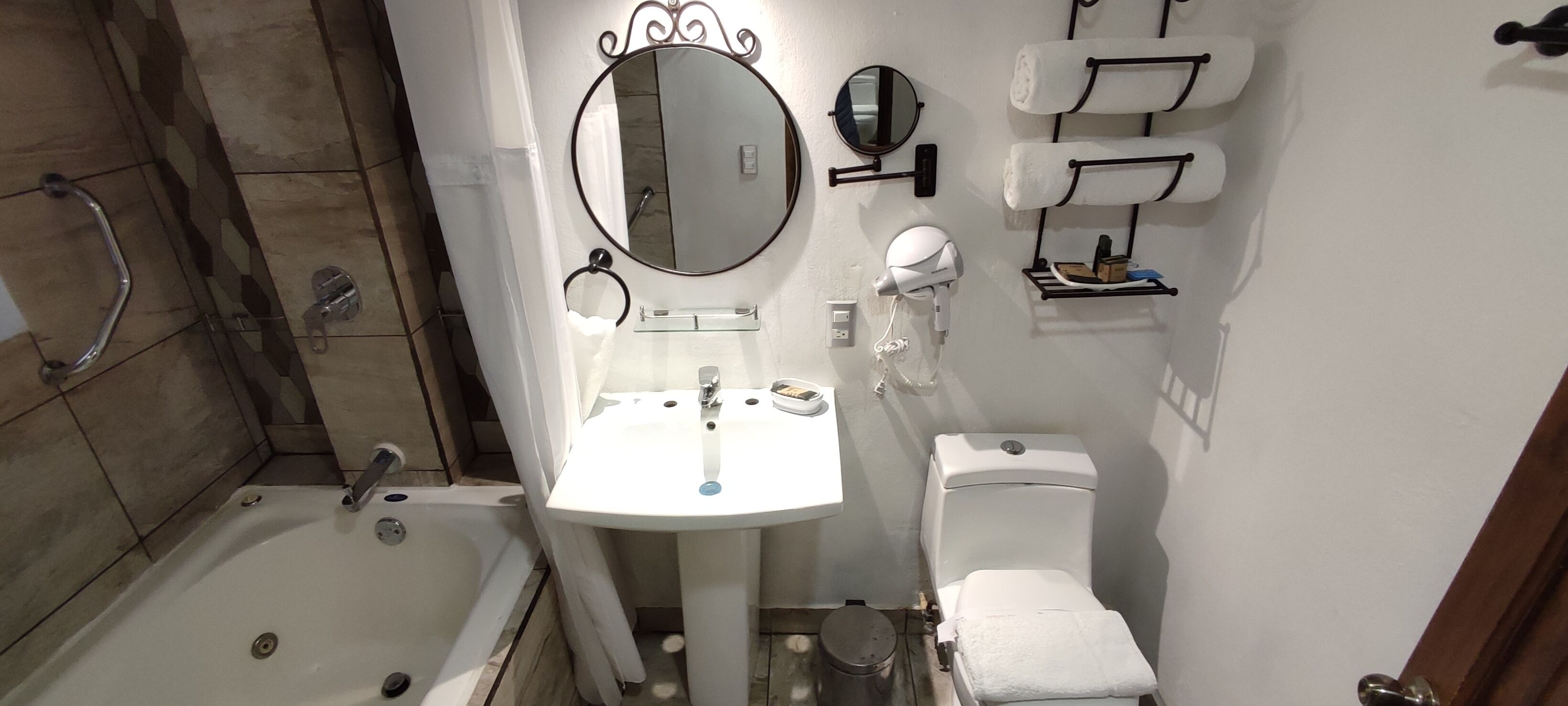 A bathroom with a bathtub, a sink, a toilet, and a mirror.