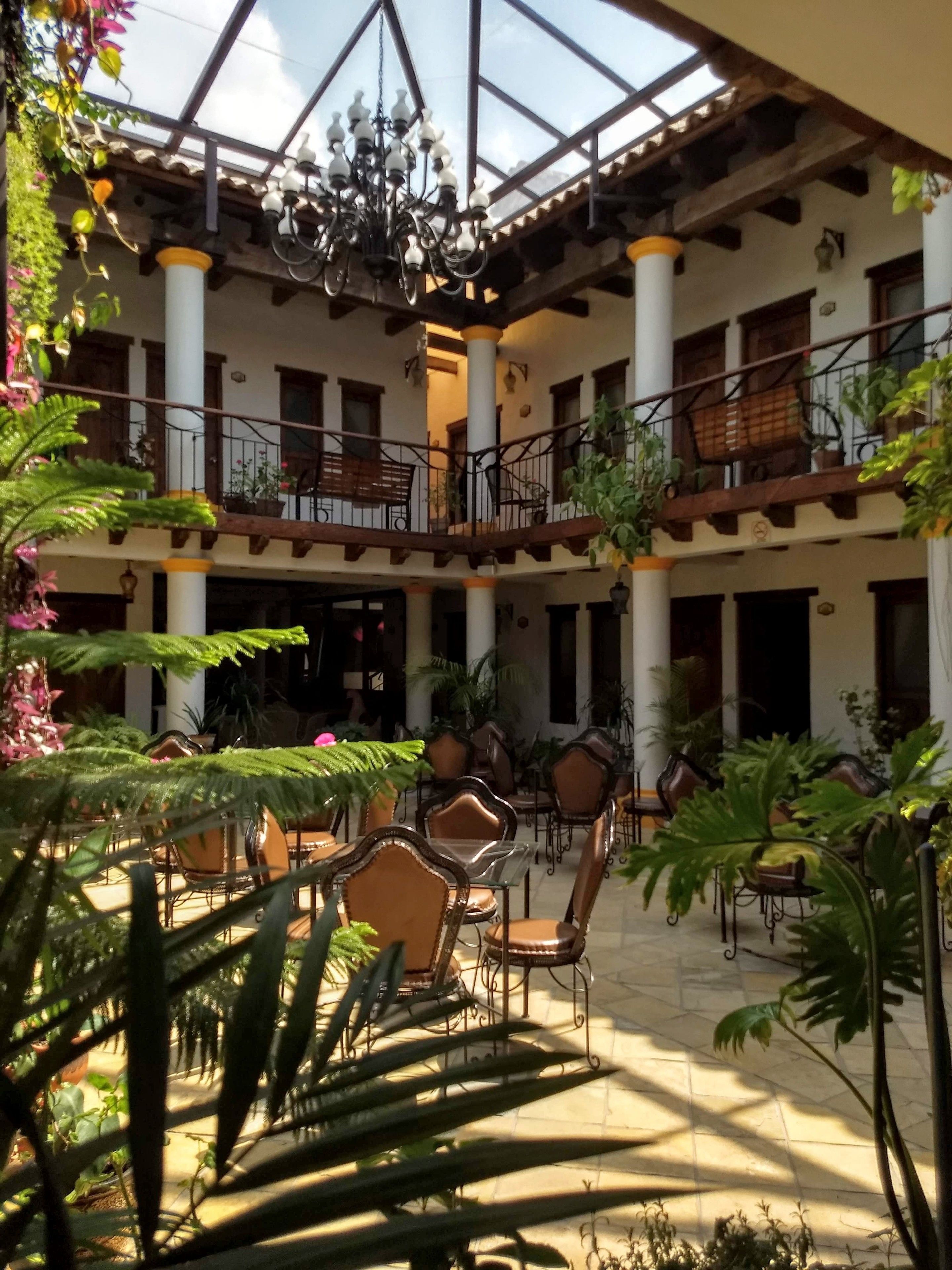 A spacious courtyard with a glass ceiling, multiple levels of balconies, and a variety of seating arrangements.