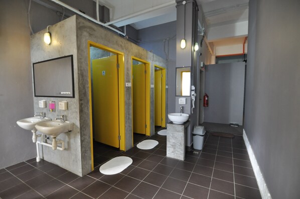 A modern bathroom with two sinks, yellow doors, a marble pedestal sink, and a mirror.
