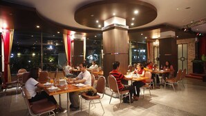 A restaurant with round tables and chairs, large windows, and a modern interior design. - Boonsiam Hotel (Krabi)