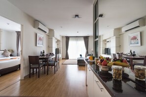 Una camera d'albergo moderna con un letto, un angolo ristoro e un bancone cucina con frutta e vasetti.