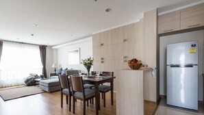 Une cuisine moderne avec des meubles en bois, un îlot central intégré et un réfrigérateur en acier inoxydable.